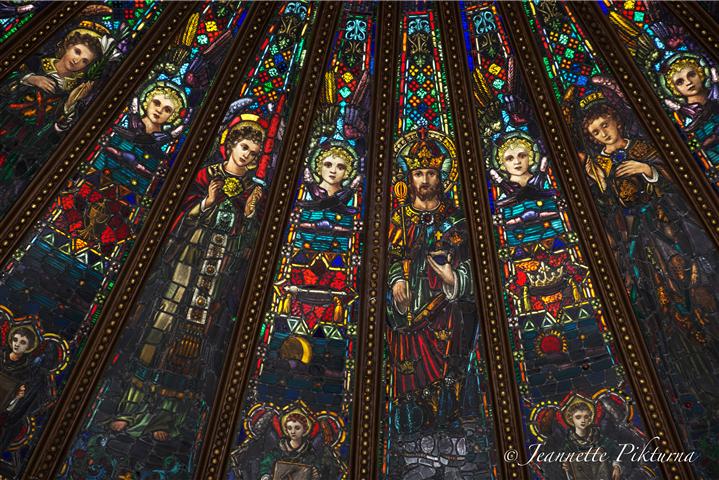 Detail of church's stained glass skylight, the theme of which is Christ the King. "The central panel shows Christ reigning as Lord of the kingdom that we pray will come." Surrounding panels contain figures of angels and symbols both of Christ's suffering and His glorification. Photo credit: Jeannette Pikturna.