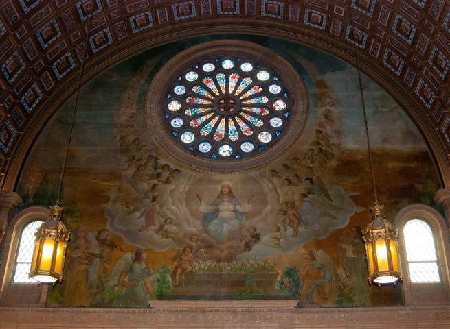 Much of the left (east) transept wall of Blessed Trinity Church is covered by this large painting of the Assumption of Mary into Heaven by Joseph Mazur. The theme of the artist’s rendering “is the crowning of [the] good life of Mary with heavenly joy; … the goal of every Christian’s life.” The painting parallels Mr. Mazur’s mural of the Ascension of Christ on the opposite transept. (Rev. Walter Kern’s Guidebook to Blessed Trinity R. C. Church, p. 45). Joseph Mazur also painted the mural in the great dome of the church. Photo credit: Steve Mangione.