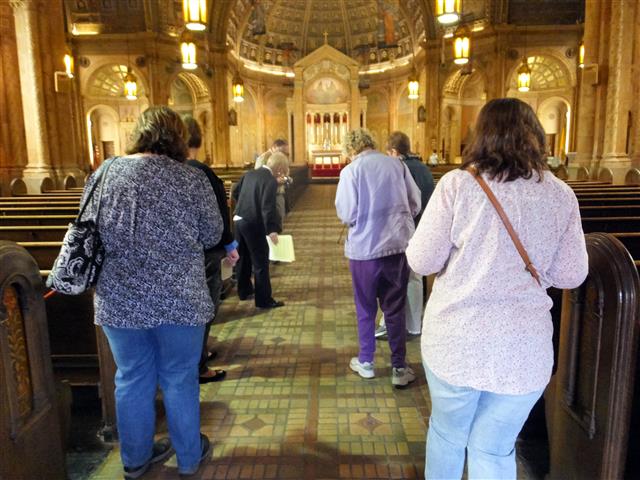 Docent Marianne Pernick points our symbols in floor tiles as visitors enter the church's nave on Saturday, May 21.